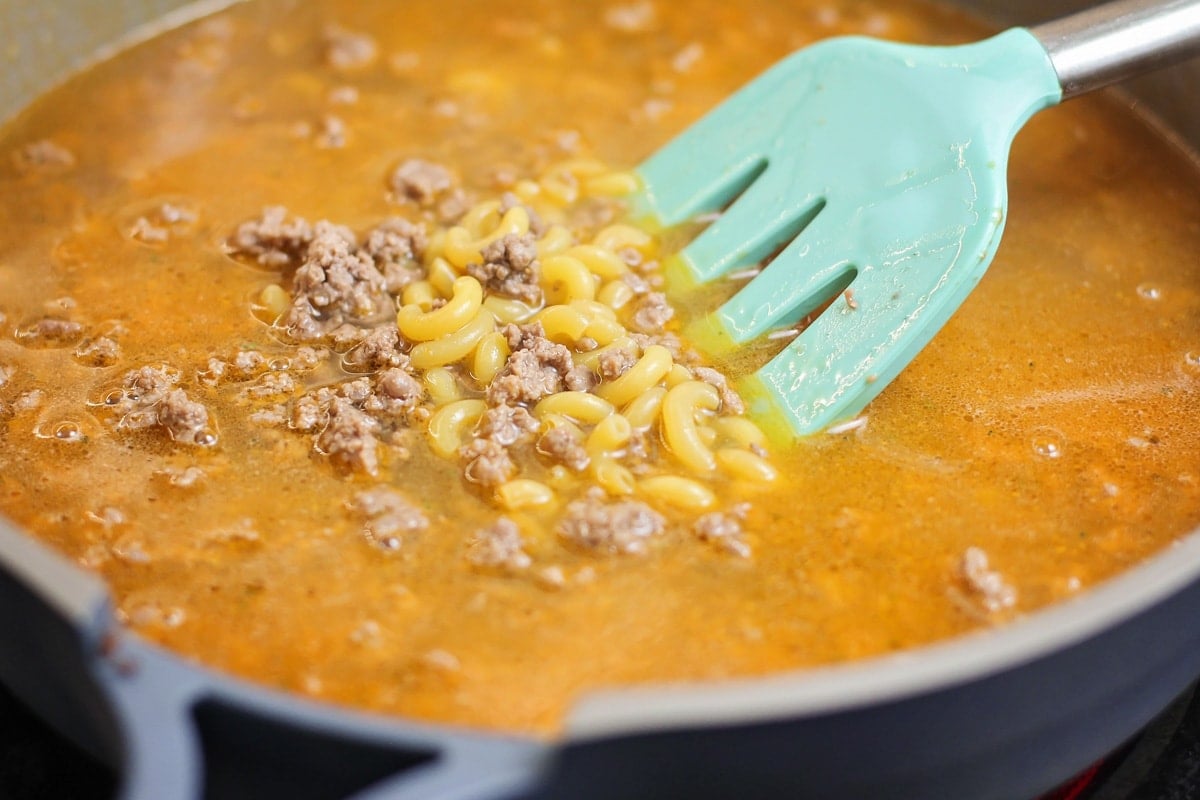 Better than the box, Homemade Hamburger Helper is a perfect one-pot meal that comes together in under 30 minutes! Adding pasta to the pot for homemade hamburger helper.
