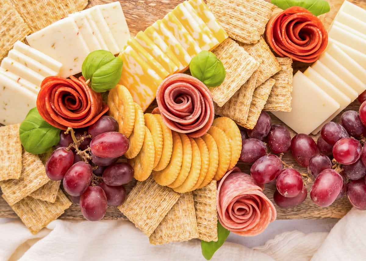 Pepperoni roses are a fun and easy way to elevate your charcuterie board, adding a beautiful and delicious touch. Pepperoni and salami roses rolled and placed on a charcuterie board.
