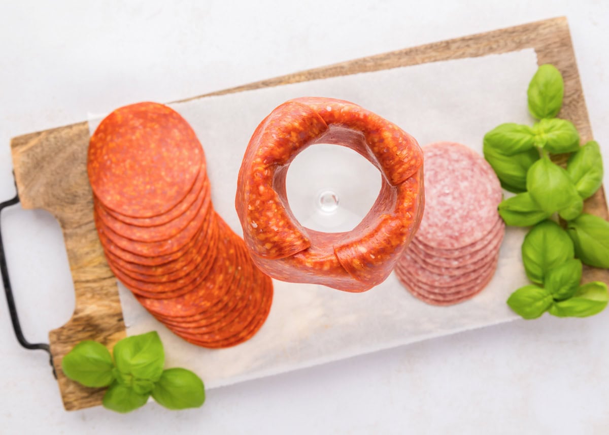 Pepperoni roses are a fun and easy way to elevate your charcuterie board, adding a beautiful and delicious touch. Placing pepperoni slices around the rim of the jar.