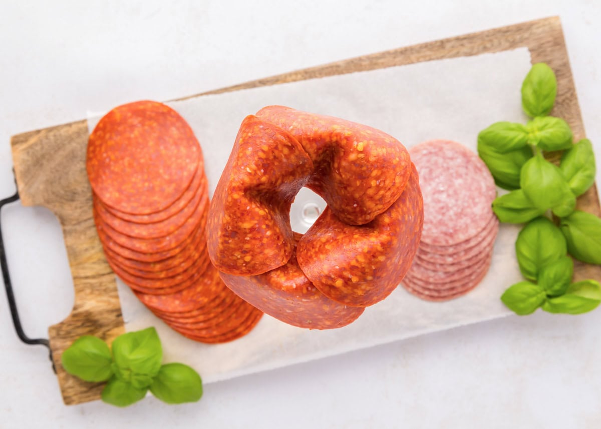 Pepperoni roses are a fun and easy way to elevate your charcuterie board, adding a beautiful and delicious touch. Layering pepperoni around the rim of a glass jar.