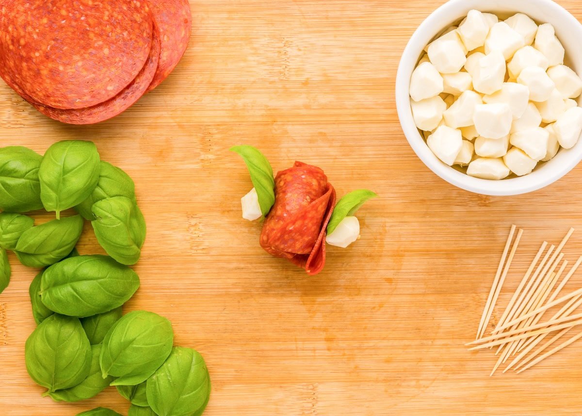 Create beautiful {and delicious} pepperoni rose skewers with only 3 ingredients and a few simple steps - a picture-perfect appetizer! Adding mozzarella and basil to the skewers.